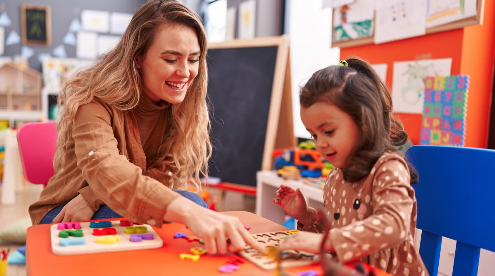 A kindergarten teacher working with young children at a classroom table