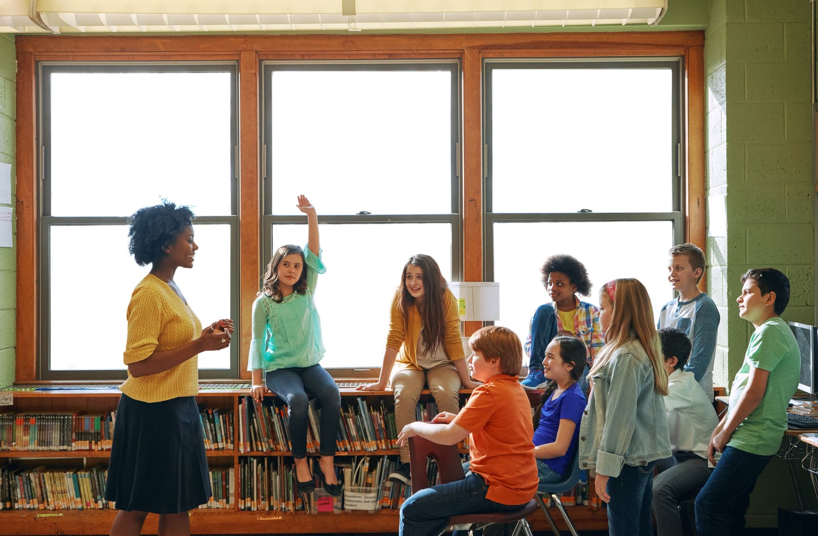 A middle school teacher helping early-adolescent students at their desks
