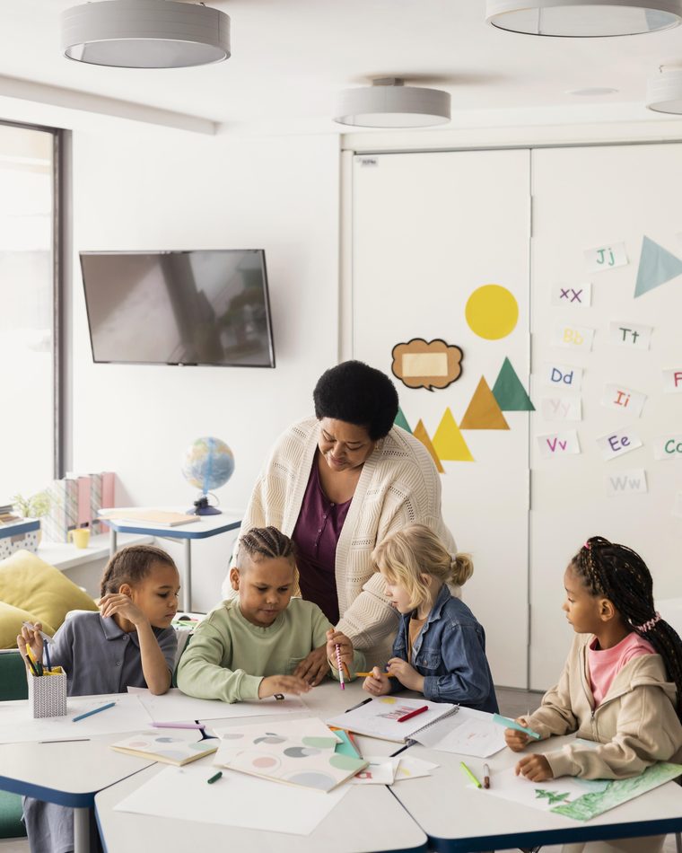 Elementary education teacher and students in a bright classroom