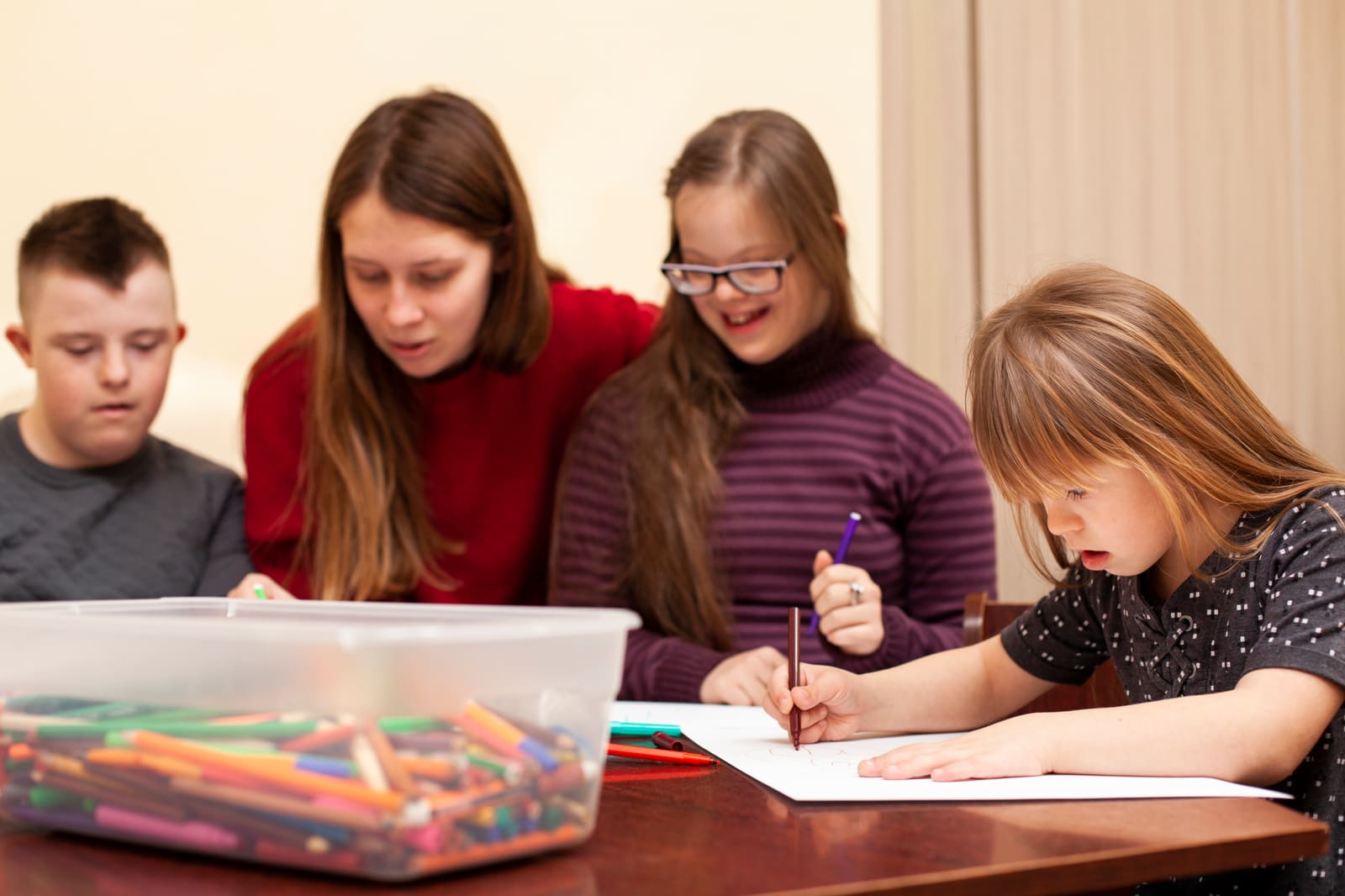 A special education teacher working closely one-on-one with a student in the classroom
