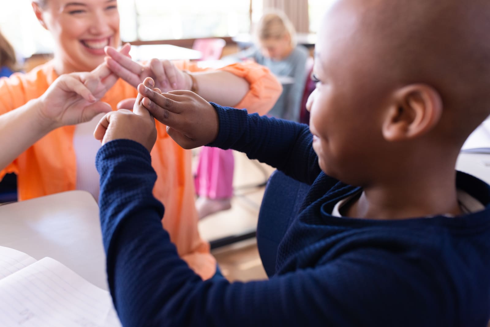 A special education teacher working closely one-on-one with a student in the classroom