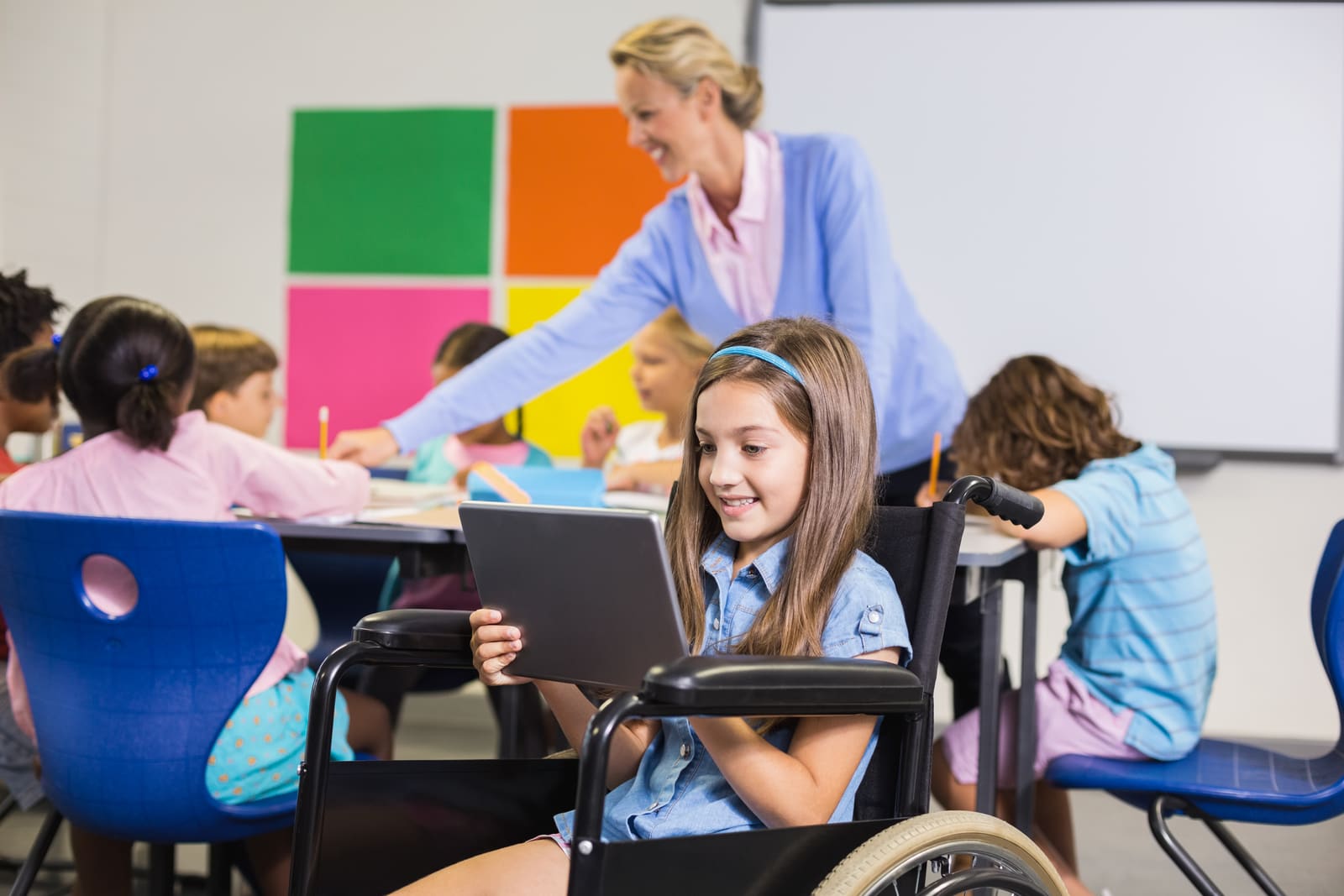 A special education teacher working closely one-on-one with a student in the classroom