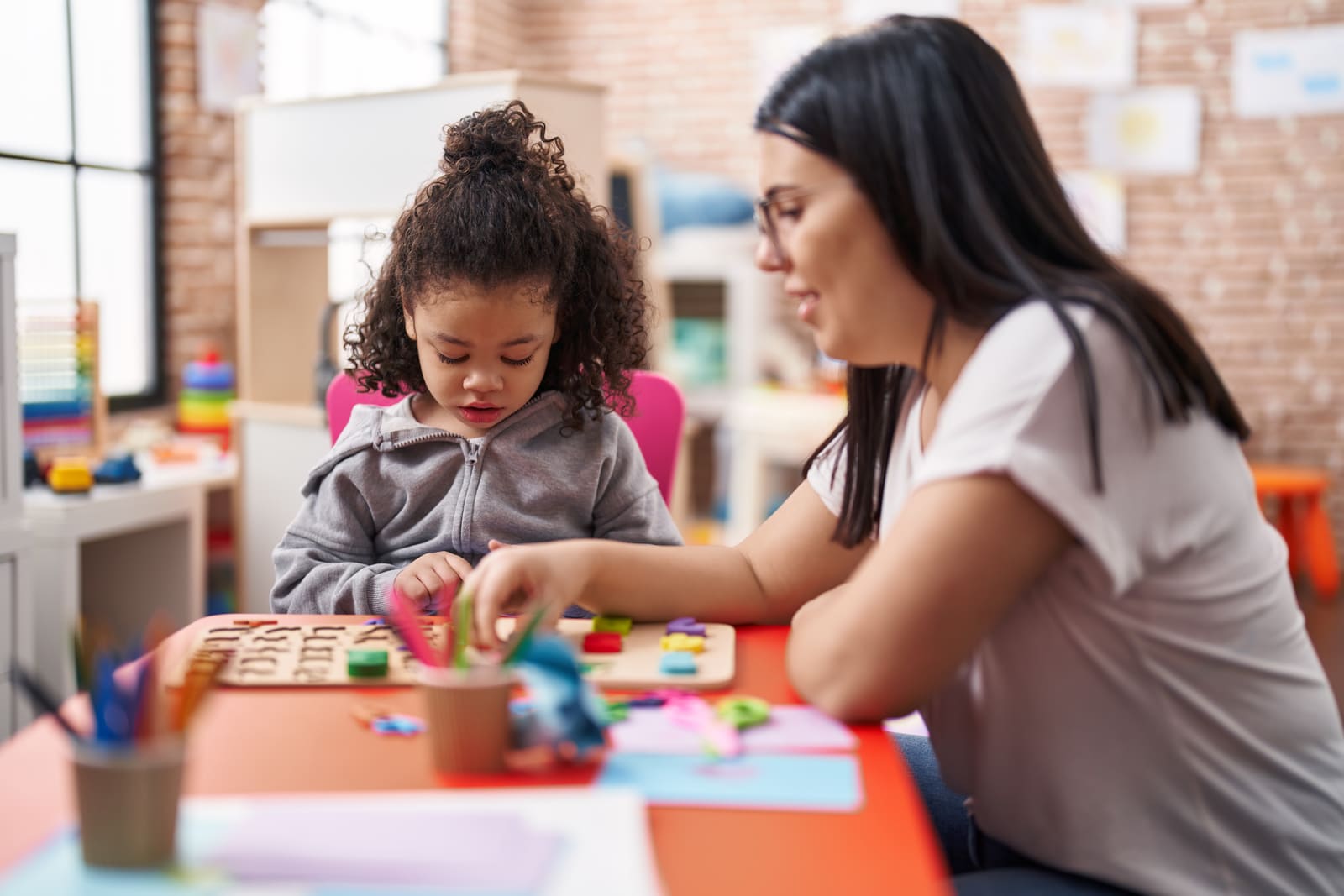 A special education teacher working closely one-on-one with a student in the classroom