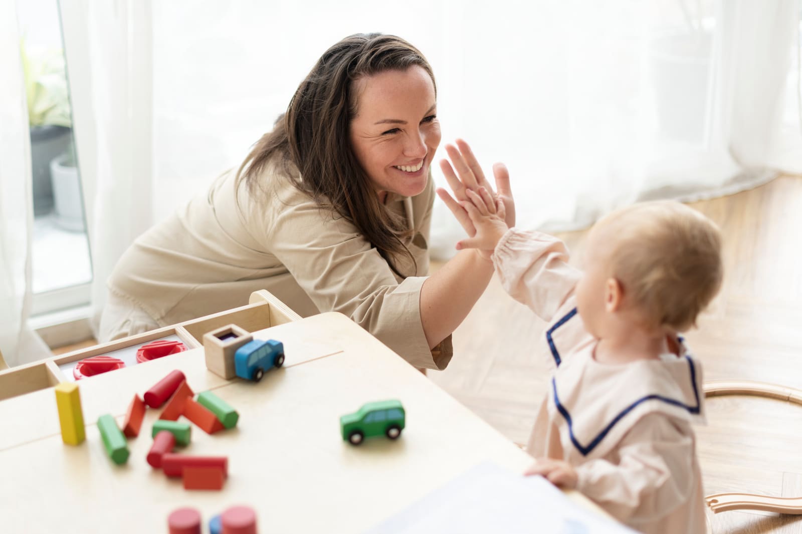 An early childhood education teacher working with young children as they learn in a bright classroom
