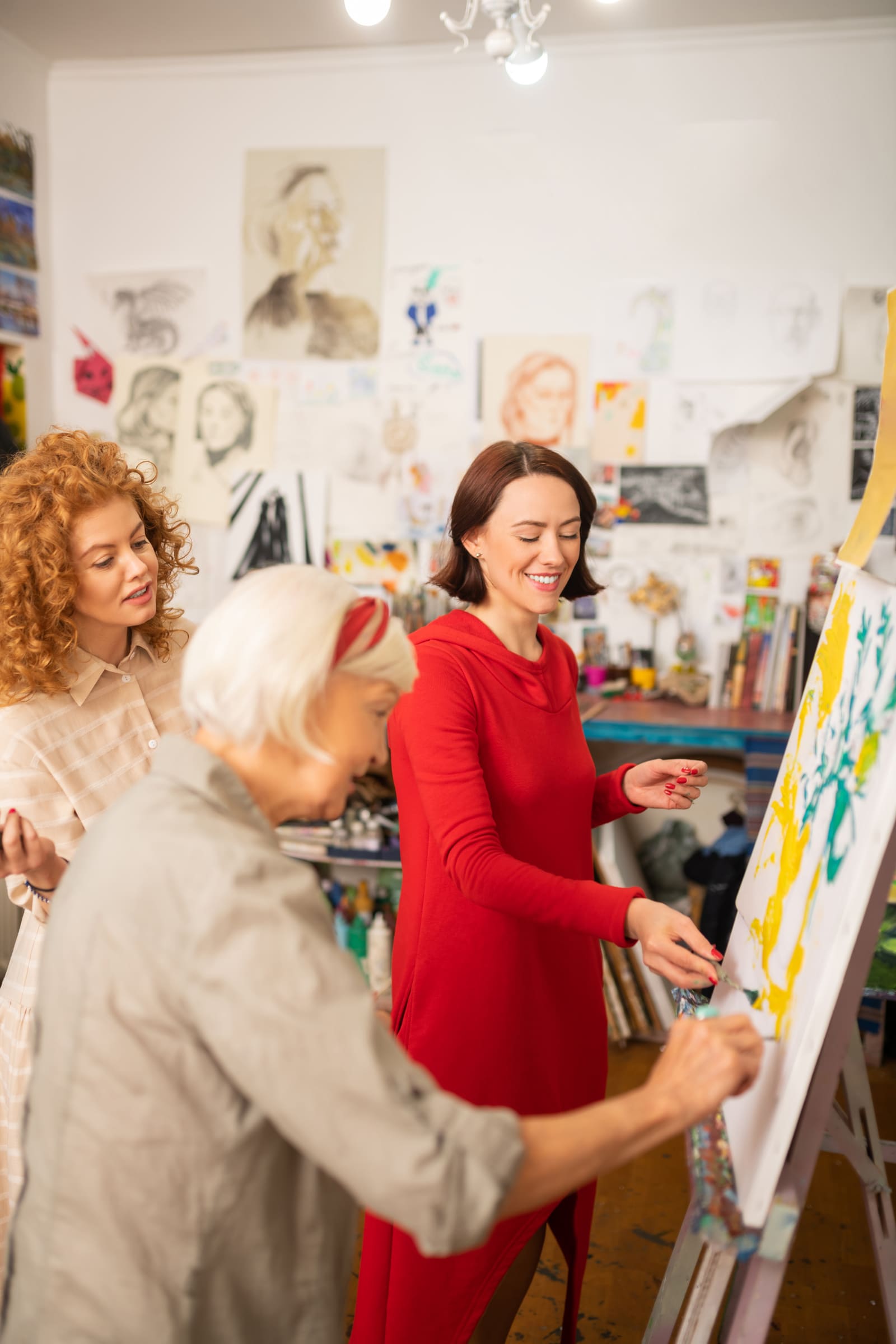 An art teacher helping a student at an easel in a bright studio classroom