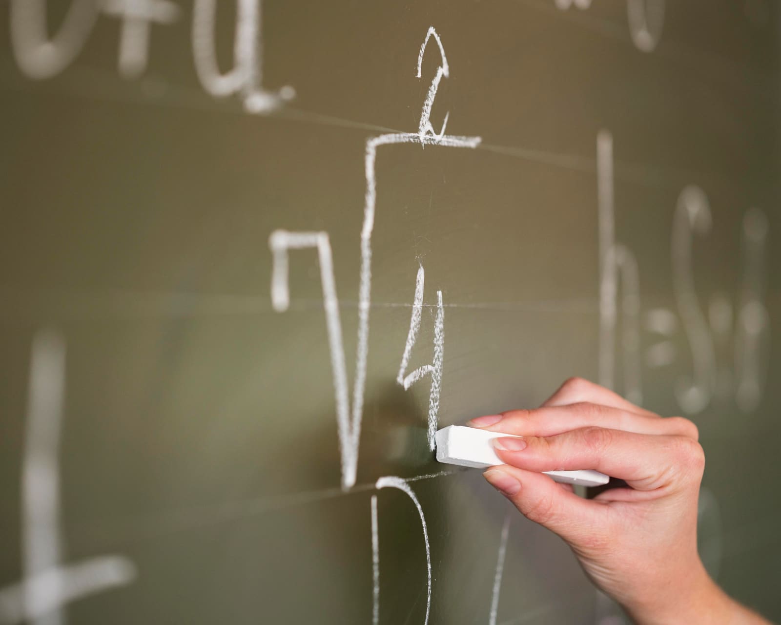 A mathematics teacher working through an equation on the whiteboard with students