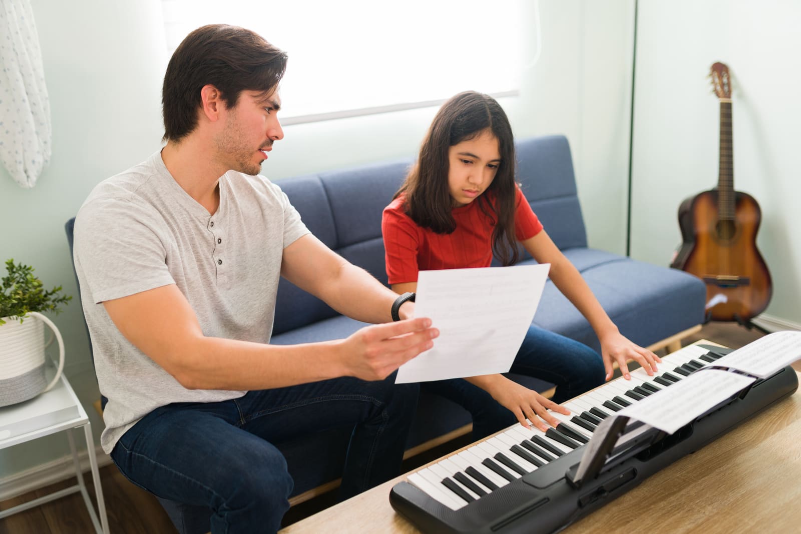 A music education teacher guiding a student reading sheet music at a keyboard