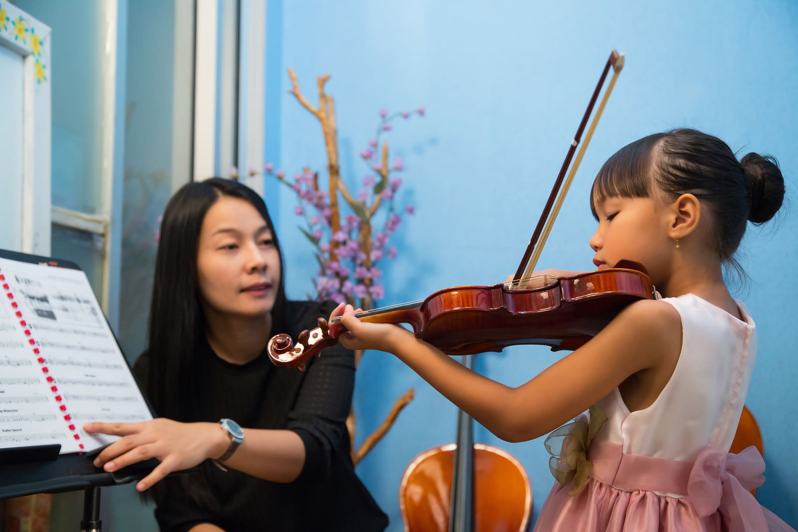 A music education teacher guiding a student reading sheet music at a keyboard