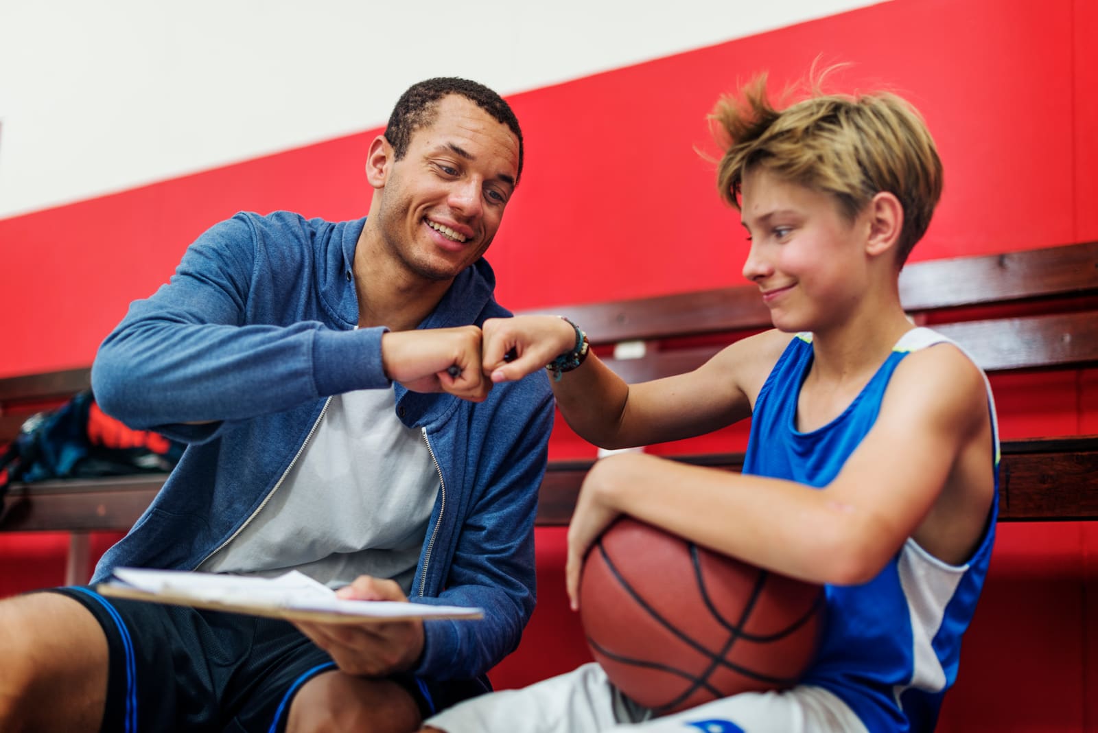 A physical education teacher leading elementary students through a ball drill in the school gym