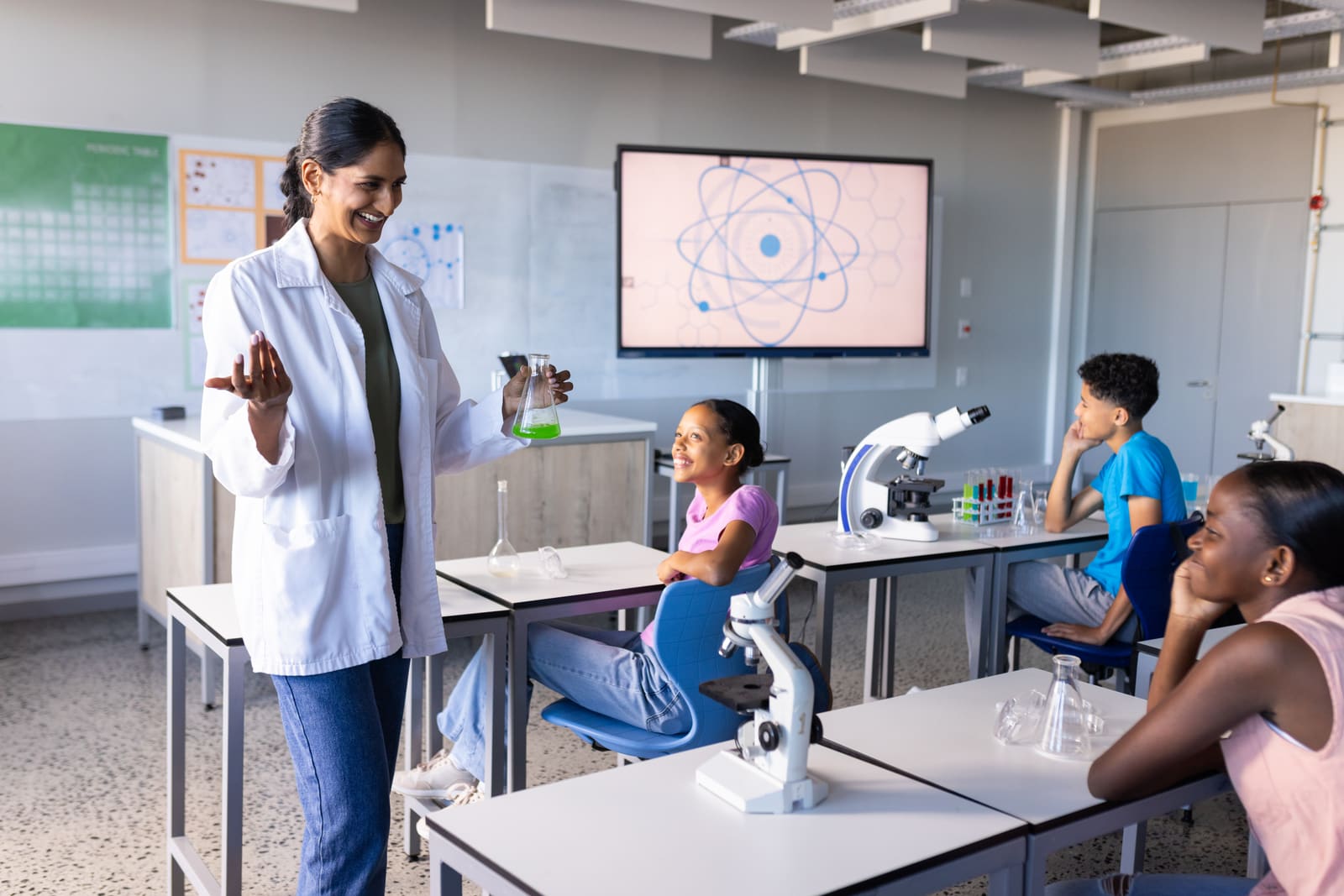 A science teacher guiding students through a hands-on experiment at a classroom lab bench
