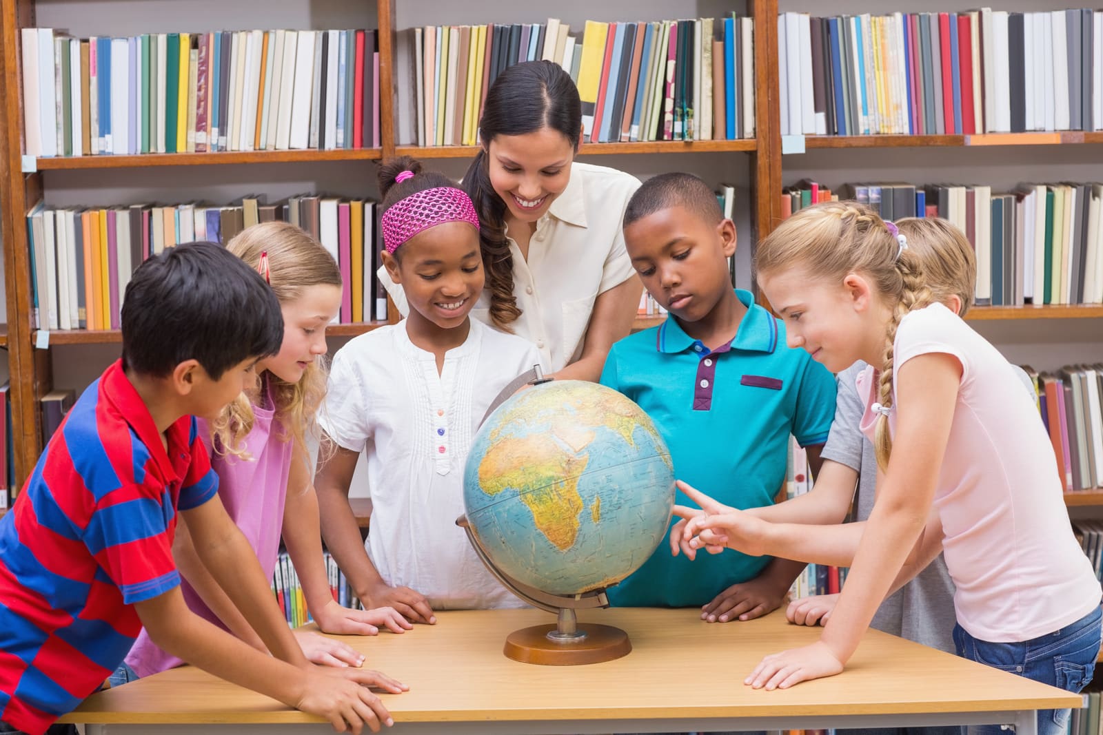 A social studies teacher pointing to a world map while teaching a class