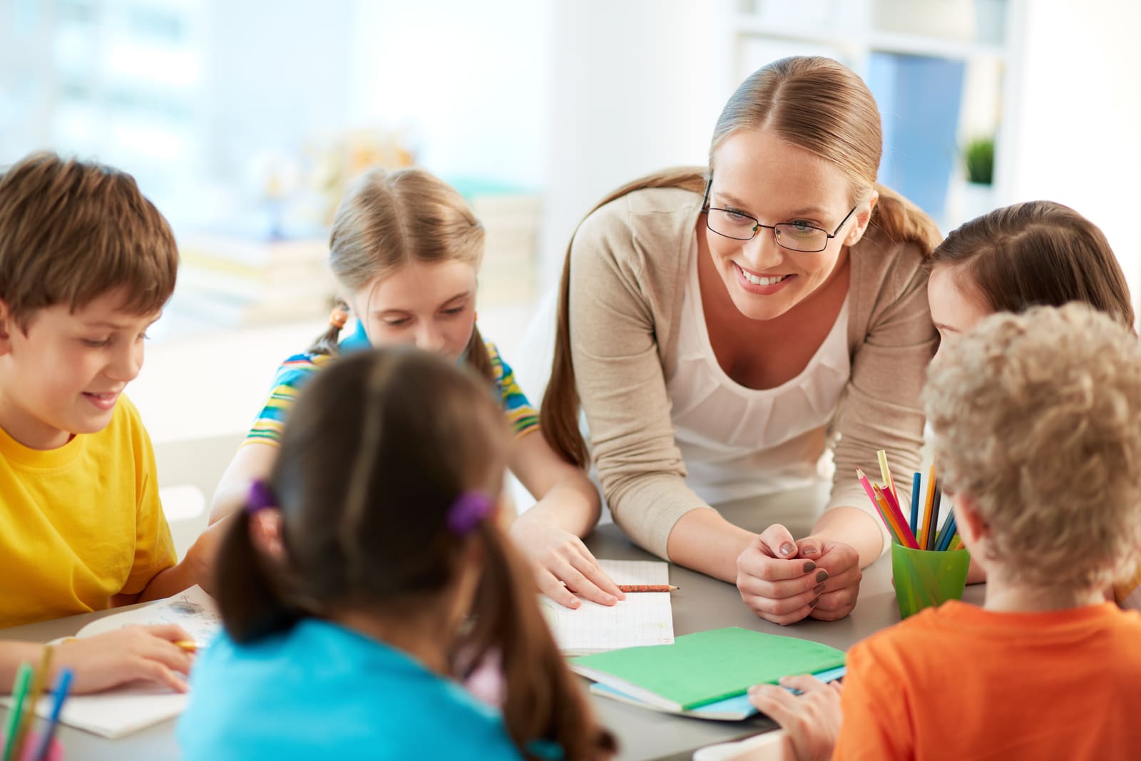 An elementary school teacher reading with a small group of young students