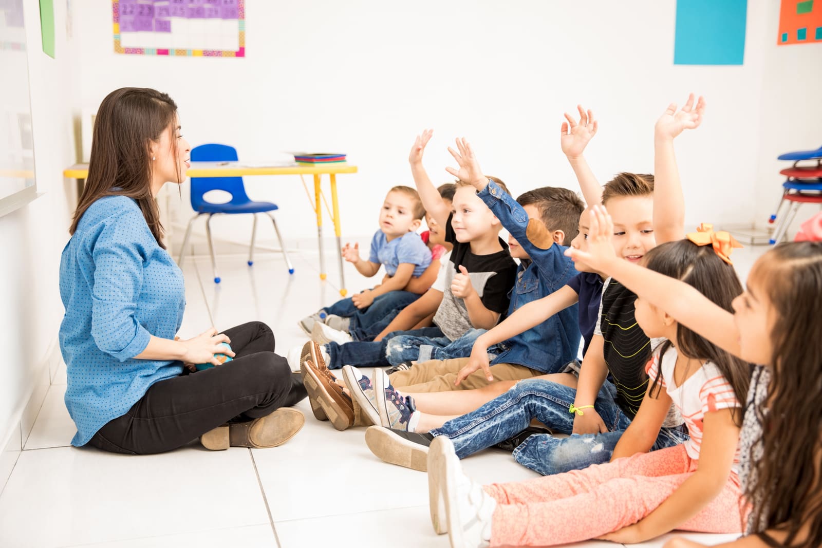 A preschool teacher reading a picture book to a group of preschoolers